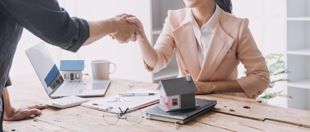 Dana and Alan Burk shaking hands during a real estate consultation.