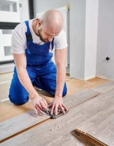 Man installing hardwood flooring, focused on the task.